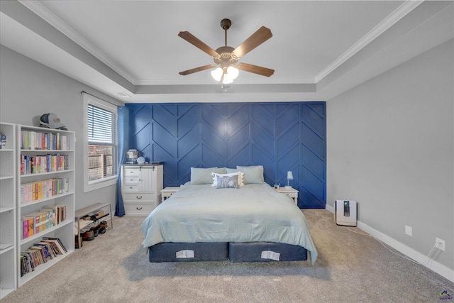 bedroom with a tray ceiling, carpet floors, baseboards, and crown molding