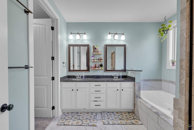 bathroom with double vanity, marble finish floor, a garden tub, and a sink