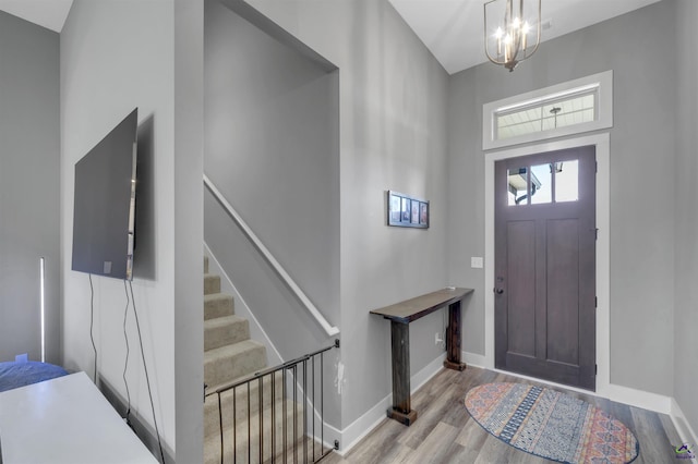 entrance foyer featuring stairway, wood finished floors, baseboards, and a chandelier