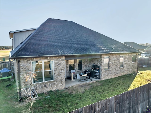 rear view of house featuring a yard, a patio, roof with shingles, and a fenced backyard