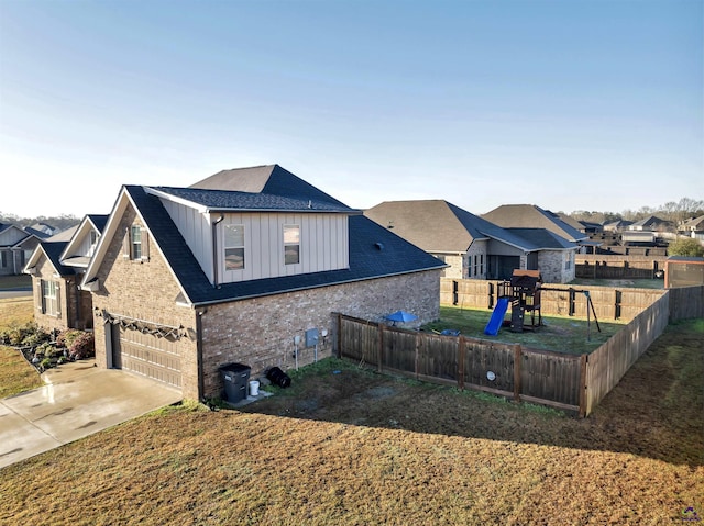 exterior space with an attached garage, a yard, concrete driveway, board and batten siding, and brick siding