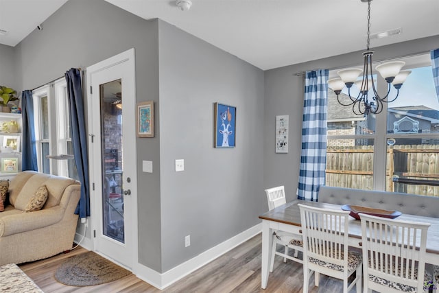 dining space featuring a chandelier, visible vents, baseboards, and wood finished floors