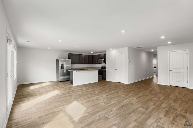 kitchen featuring a center island with sink, light wood-style flooring, open floor plan, and stainless steel appliances