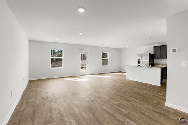 unfurnished living room with recessed lighting, baseboards, and light wood-style floors