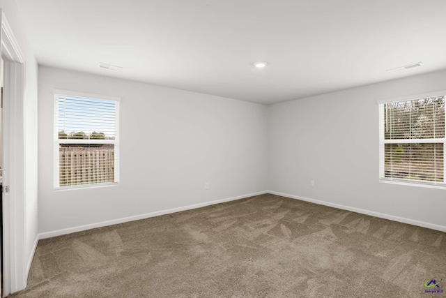 carpeted empty room with visible vents and baseboards