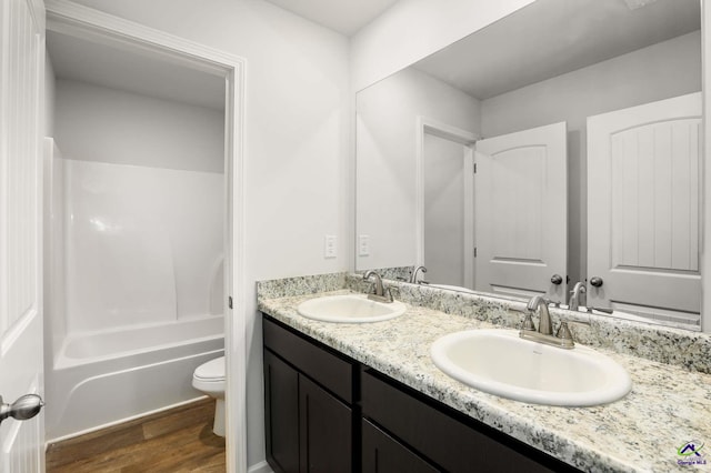 full bath featuring double vanity, toilet, wood finished floors, and a sink