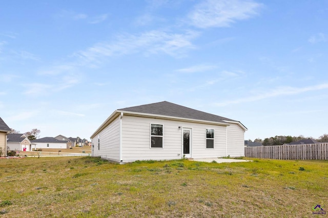 rear view of property featuring fence and a lawn