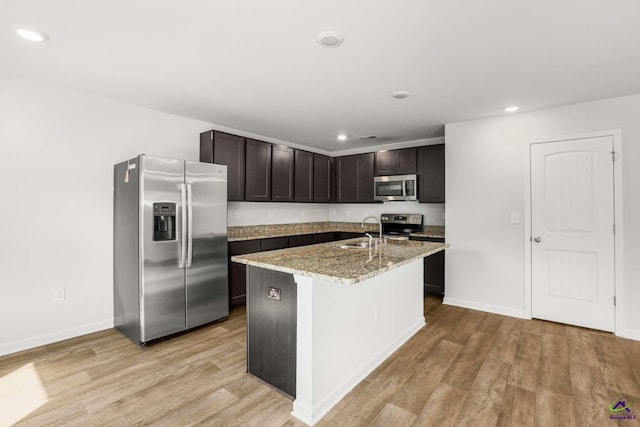 kitchen featuring light stone counters, recessed lighting, stainless steel appliances, dark brown cabinetry, and light wood-type flooring