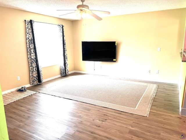 unfurnished living room with baseboards, a textured ceiling, ceiling fan, and wood finished floors