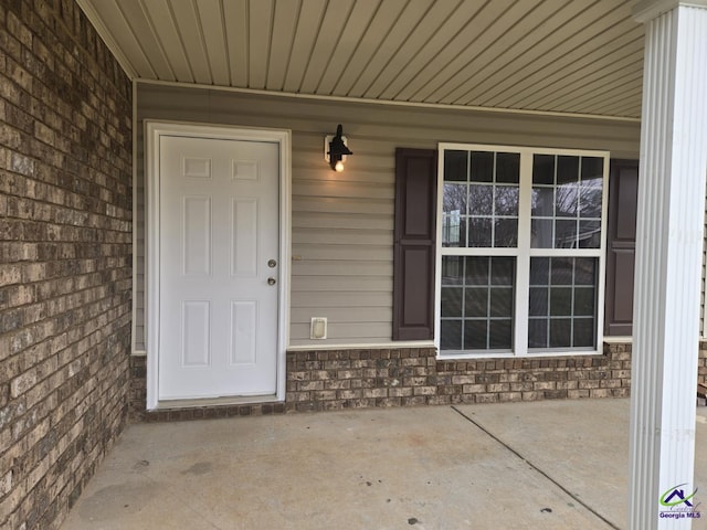 entrance to property featuring a porch, brick siding, and stone siding