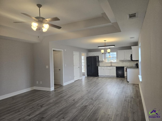 unfurnished living room with visible vents, baseboards, dark wood-style flooring, and ceiling fan with notable chandelier