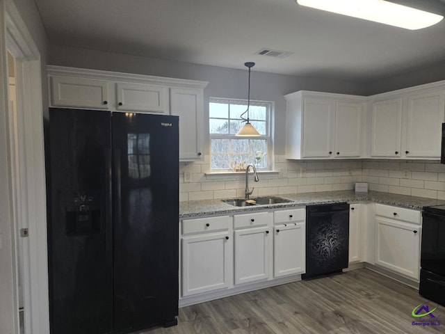 kitchen with backsplash, wood finished floors, white cabinets, black appliances, and a sink