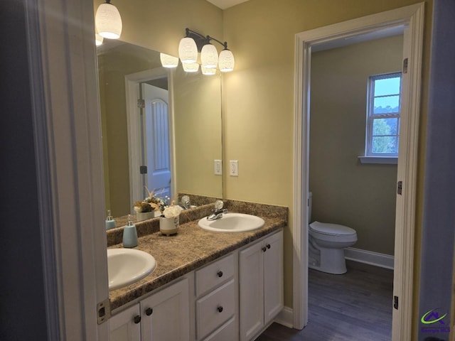 full bathroom with double vanity, toilet, baseboards, and a sink