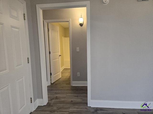 hall with baseboards and dark wood-type flooring