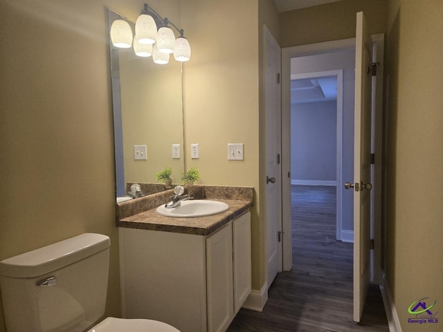 bathroom featuring vanity, toilet, wood finished floors, and baseboards