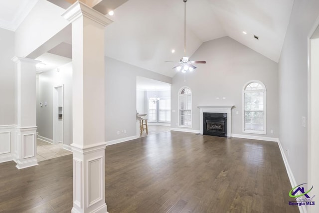 unfurnished living room with a fireplace with flush hearth, wood finished floors, ornate columns, and ceiling fan