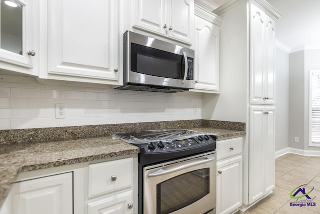 kitchen featuring ornamental molding, appliances with stainless steel finishes, white cabinets, decorative backsplash, and baseboards