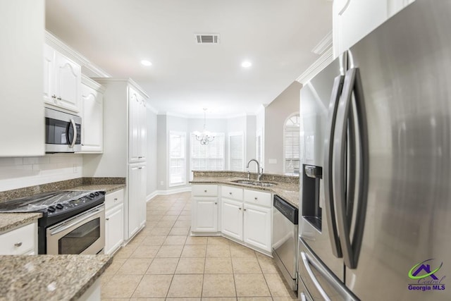 kitchen featuring visible vents, ornamental molding, appliances with stainless steel finishes, white cabinets, and a sink