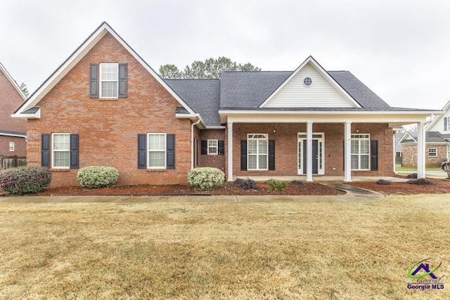 view of front of house featuring a front lawn, brick siding, and roof with shingles