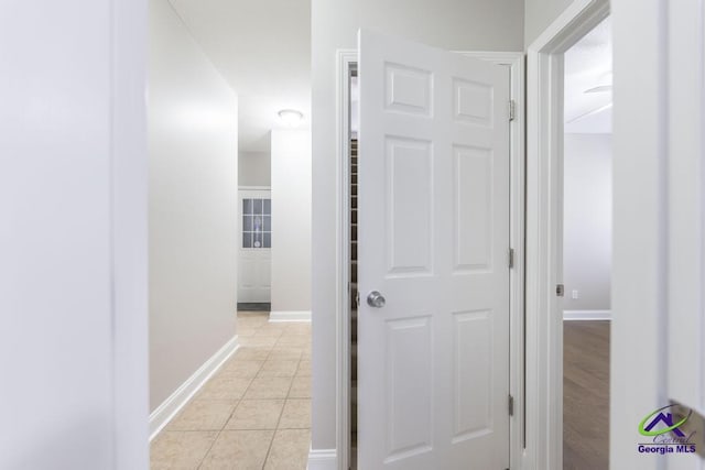 hallway featuring baseboards and light tile patterned flooring