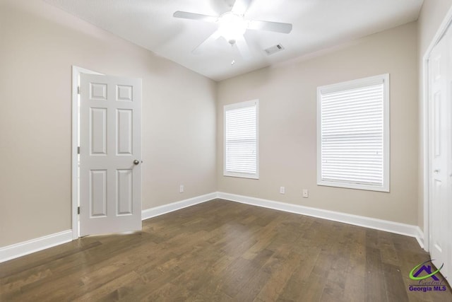 empty room with visible vents, baseboards, dark wood-type flooring, and a ceiling fan