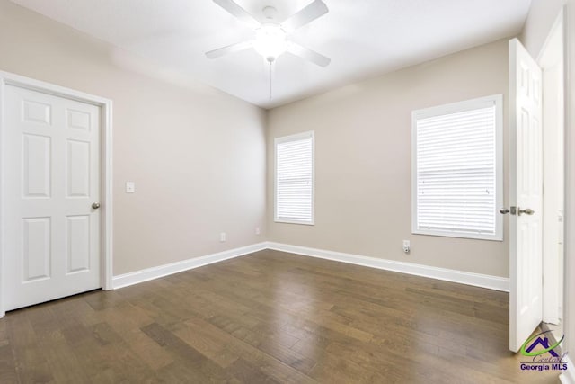 unfurnished room with baseboards, a ceiling fan, and dark wood-style flooring