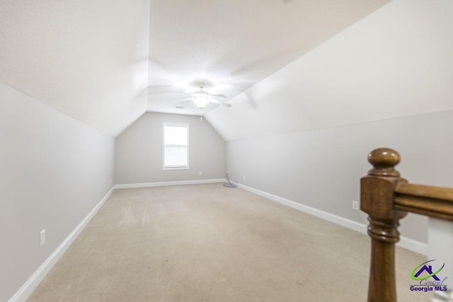 additional living space featuring light colored carpet, baseboards, ceiling fan, and vaulted ceiling