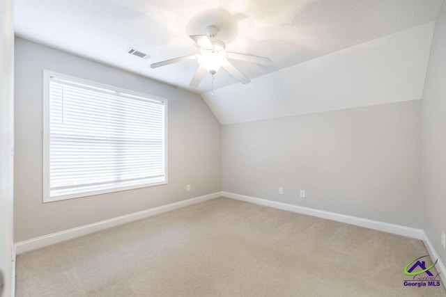 additional living space with visible vents, lofted ceiling, light colored carpet, and baseboards