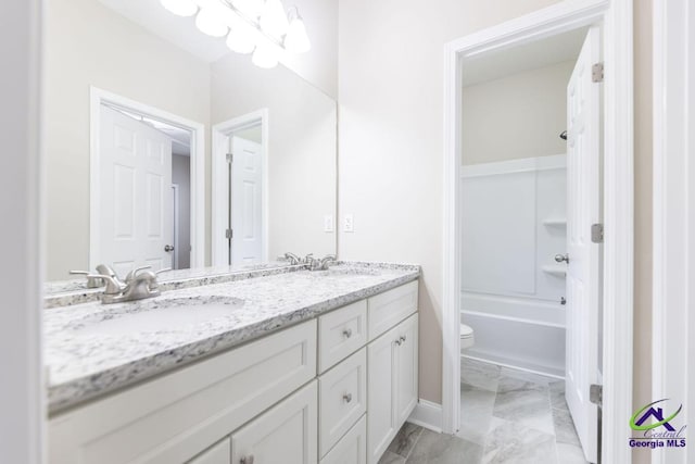 bathroom with double vanity, toilet, marble finish floor, and a sink