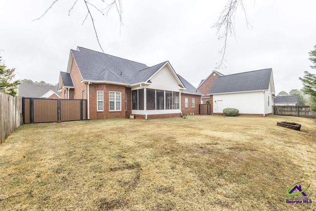 back of house featuring a yard, brick siding, a fenced backyard, and a sunroom