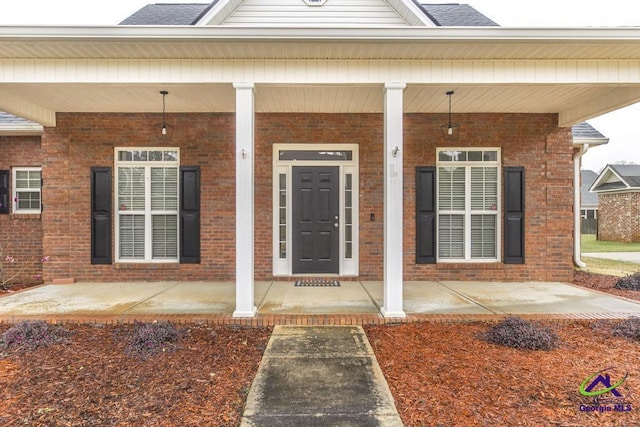 doorway to property featuring brick siding and covered porch