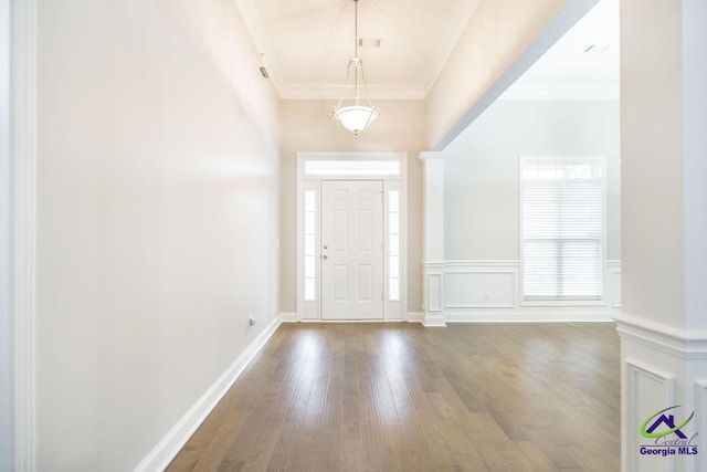 foyer entrance with a decorative wall, wood finished floors, a wainscoted wall, and ornamental molding