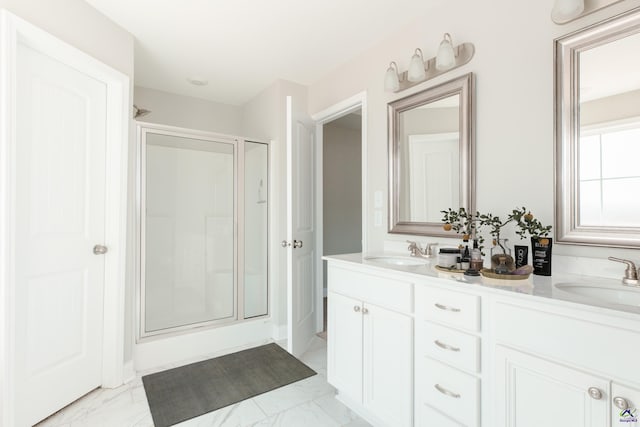 bathroom with double vanity, a stall shower, marble finish floor, and a sink