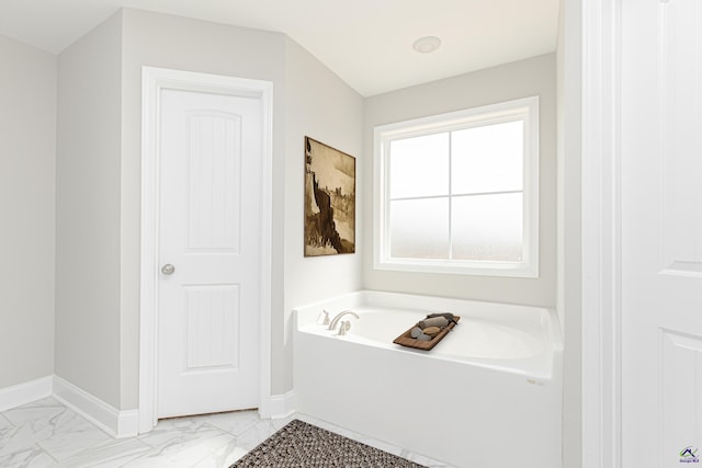 full bathroom featuring a garden tub, baseboards, and marble finish floor