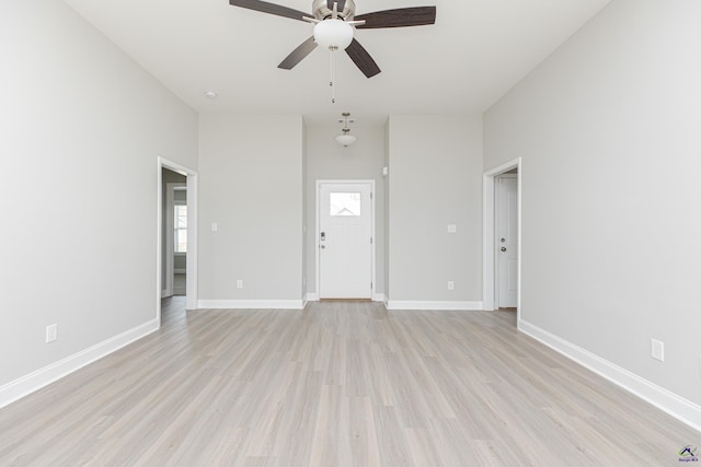 unfurnished living room featuring baseboards, light wood-type flooring, and ceiling fan