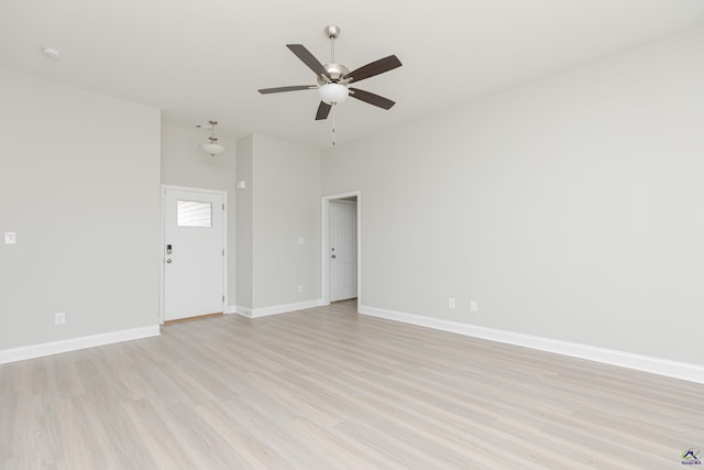 spare room featuring a ceiling fan, baseboards, and light wood finished floors