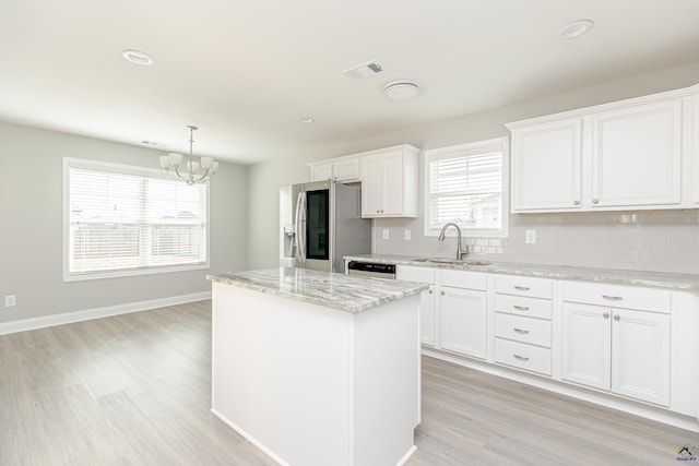 kitchen with visible vents, a kitchen island, a sink, stainless steel fridge, and a chandelier