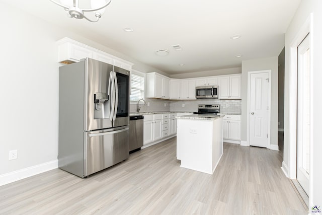 kitchen with decorative backsplash, light wood finished floors, white cabinetry, and stainless steel appliances