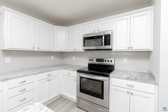 kitchen with decorative backsplash, white cabinetry, and stainless steel appliances