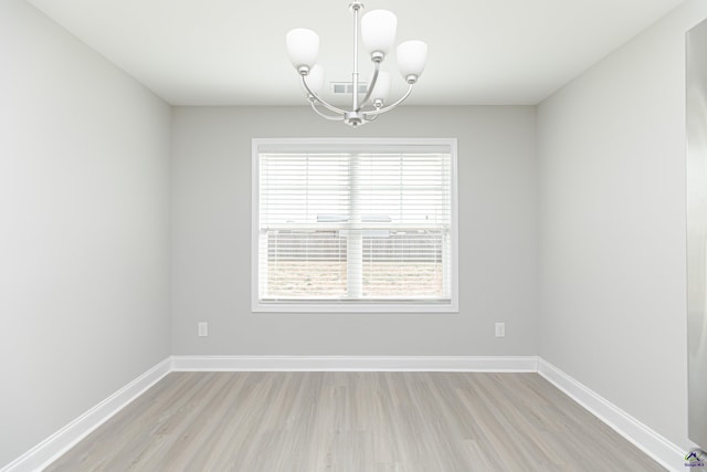 unfurnished room with a notable chandelier, visible vents, baseboards, and light wood finished floors