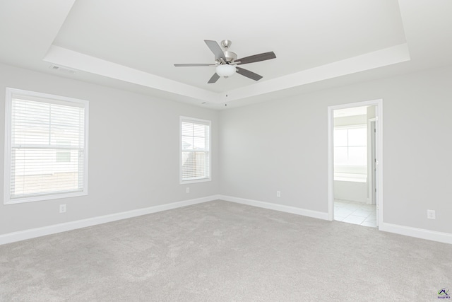 unfurnished room featuring visible vents, baseboards, ceiling fan, light colored carpet, and a tray ceiling