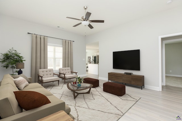 living room with light wood-style flooring, a ceiling fan, visible vents, and baseboards