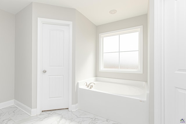 full bathroom featuring a bath, baseboards, and marble finish floor