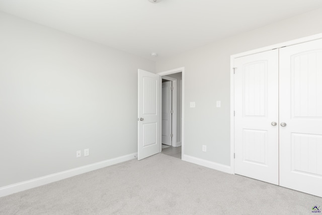 unfurnished bedroom featuring baseboards, a closet, and light carpet