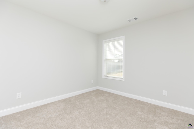 empty room featuring light carpet, visible vents, and baseboards