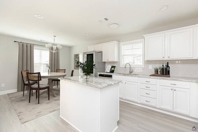 kitchen with visible vents, a kitchen island, a chandelier, smart refrigerator, and a sink