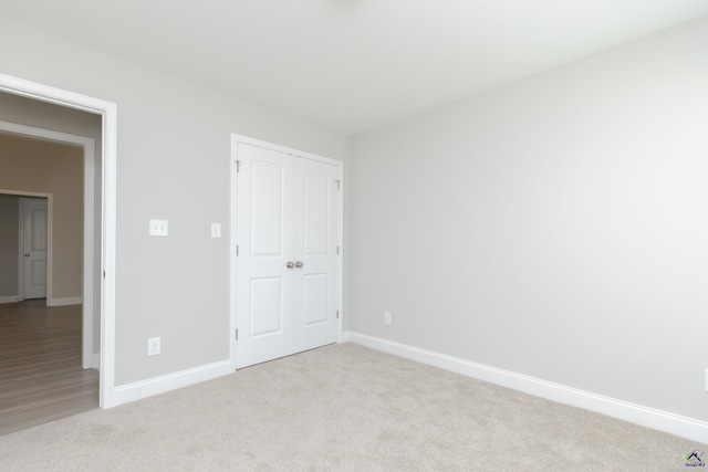 unfurnished bedroom with baseboards, a closet, and light carpet