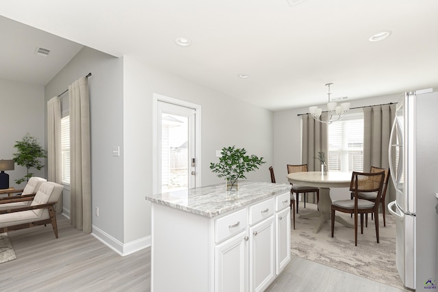 kitchen with visible vents, an inviting chandelier, freestanding refrigerator, light wood-style floors, and white cabinetry