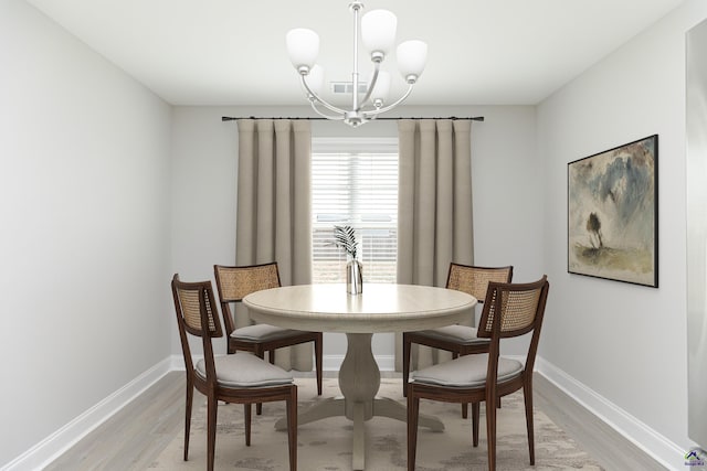 dining area featuring light wood-type flooring, baseboards, and a notable chandelier