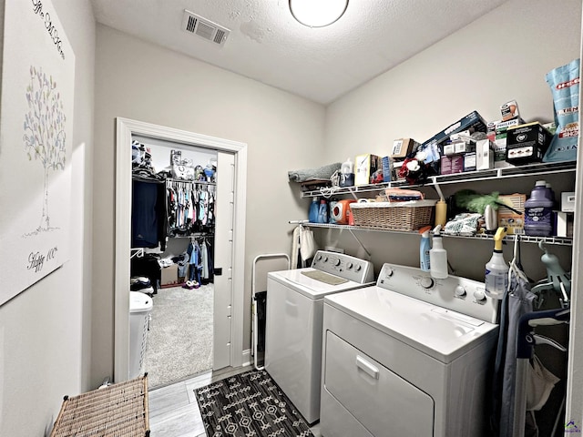 laundry area featuring visible vents, independent washer and dryer, a textured ceiling, wood finished floors, and laundry area